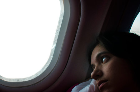 girl looking out the window of a plane