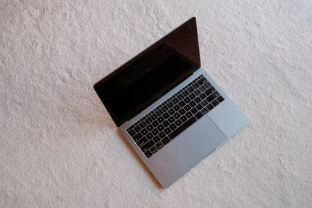 grey and black computer on soft and light floor. no people.