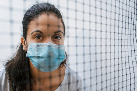 white caucasian brunette girl with blue medical face mask, looking at camera, saying stop virus with...