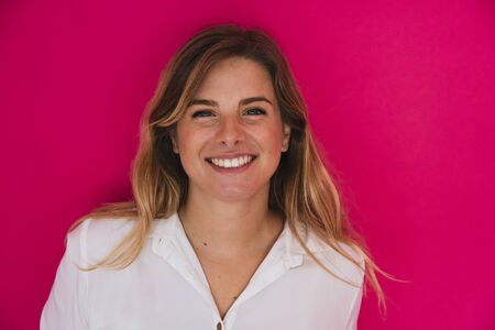 happy, young, white, blonde, caucasian, girl, in white shirt on pink background looking at camera smiling, beautiful businesswoman, closeupの写真素材