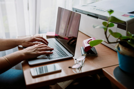 Caucasian girl working freelance at home in wooden desk with the light of the window, writing in the...