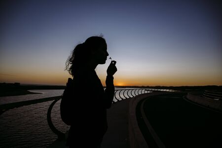 Stock photo of a silhouette of a woman smelling a flower. She is unrecognizable.の写真素材