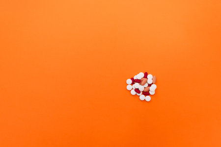 Stock photo of a bunch of different pills on an orange background. There is nobody on the picture.