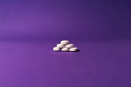 Stock photo of one pile of white pills placed on a purple background. There is nobody on the picture.の写真素材