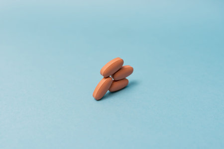 Stock photo of orange pills on a blue background. There is nobody on the picture.