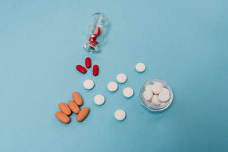 Stock photo of a bunch of different shaped and colored pills on a blue background. There is nobody on the picture.の写真素材