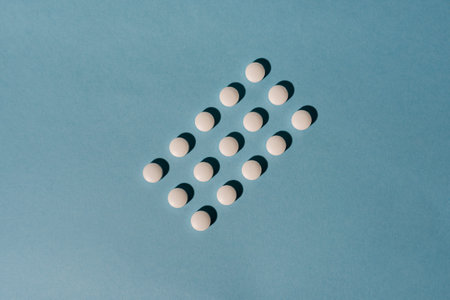 Stock photo of white pills on a blue background. There is nobody on the picture.