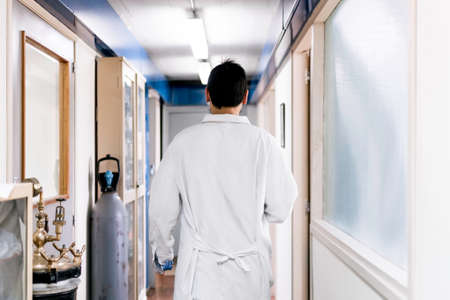 Stock photo of unrecognized scientist walking in the hall of a hospital.の写真素材