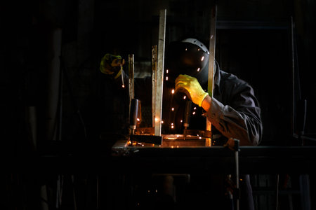 Stock photo of anonymous worker wearing protective gloves and welding helmet using blowlamp in his...