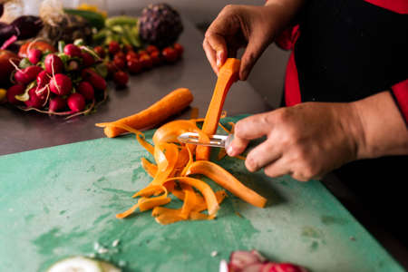 Stock photo of unrecognized chef working in the kitchen peeling carrots.の写真素材