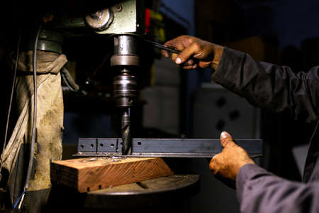 Stock photo of anonymous worker using drilling machine for metal in his workshop.の写真素材