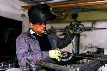 Stock photo of concentrated man wearing special gloves working in blacksmith shop.