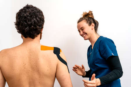 Stock photo of physiotherapist giving back massage to patient sitting in stretcher.の写真素材