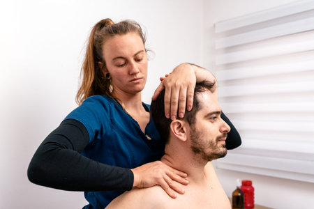 Stock photo of physiotherapist giving back massage to patient sitting in stretcher.