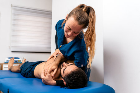 Stock photo of physiotherapist giving back massage to patient lying in stretcher.の写真素材