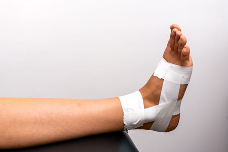 Stock photo of unrecognized patient in physiotherapy clinic with his feed wrapped in bandage.