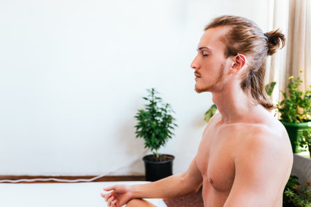 Stock photo of young man doing the lotus pose sitting on the floor.の写真素材