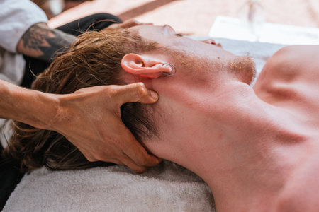 Stock photo of relaxed man enjoying neck massage while lying in a towel.の写真素材