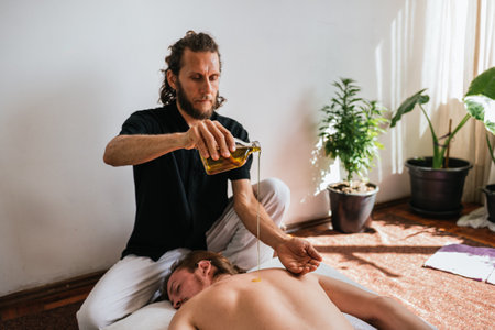 Stock photo of relaxed man enjoying back massage while lying in the floor with oils.の写真素材