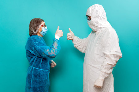 Stock photo of unrecognized person talking with healthcare worker wearing protective suit .