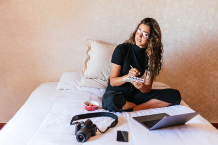 Stock photo of happy girl working with the computer in the bed and eating fruit.