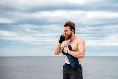Happy man using his phone outdoors after working out.の写真素材