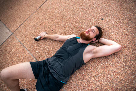 Exhausted sportive man after running and doing work out outdoors.の写真素材