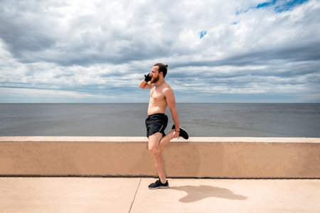 Happy man stretching after working out and using his phone outdoors.