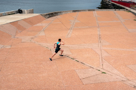 Focused bearded man running outdoors near the sea.