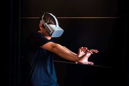 Gamer boy using virtual reality glasses having fun at home and playing video game.の写真素材