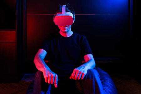 Gamer boy using virtual reality glasses having fun at home with cool lights.