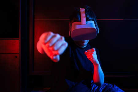 Gamer boy using virtual reality glasses having fun at home with cool lights.