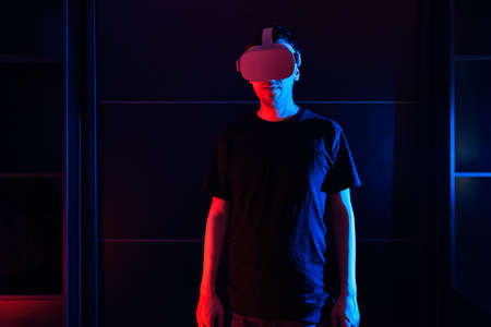 Gamer boy using virtual reality glasses having fun at home with cool lights.の写真素材