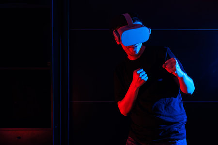 Gamer boy using virtual reality glasses having fun at home with cool lights.