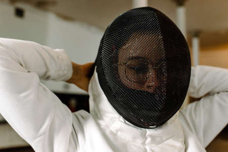 Young girl getting dressed for her fencing class in the dressing room.の写真素材