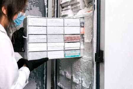 Stock photo of female scientist wearing face mask using a laboratory freezer saving covid19 vaccines.の写真素材