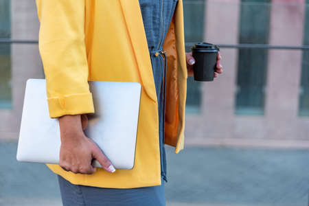 Unrecognizable businesswoman with her computer and coffee in the streetの写真素材