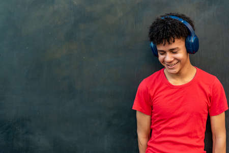 Afro latin male teenager listening music against a wallの写真素材