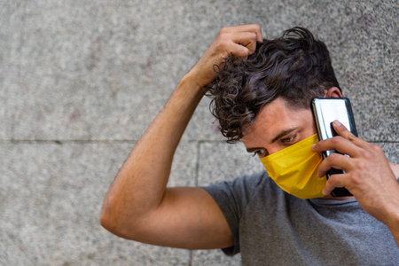 Young latin man with face mask using phone
