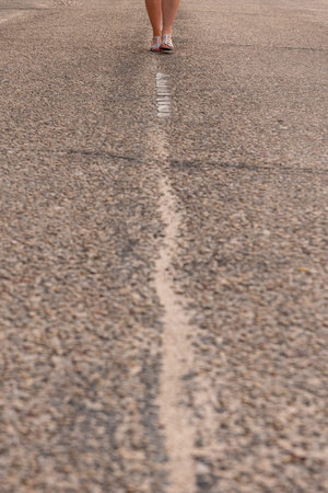 Unrecognizable girl walking in the middle of the street.