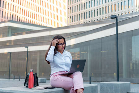 Caucasian business woman with laptop and mobile phone outdoorsの写真素材