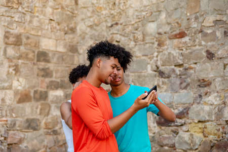 Multiethnic friends using mobile phone in the streetの写真素材