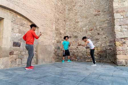 Three afro latin male friends dancing in the street and recording itの写真素材