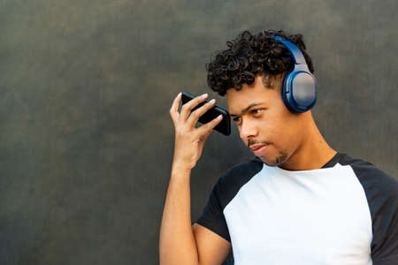 Afro latin young man listening to music against a wallの写真素材
