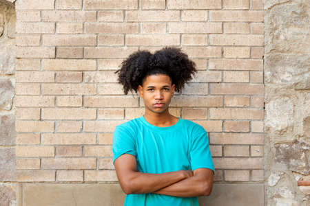 Serious young afro latin man against a brick wallの写真素材