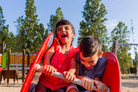 Two kids having fun playing together on a playground in a park.の写真素材