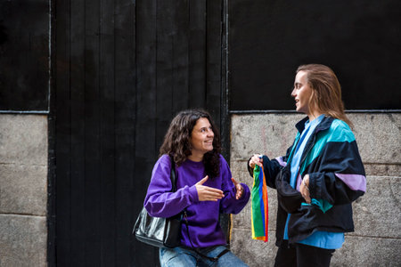 Two friends talking in the street outdoors with LGBT flag.の写真素材