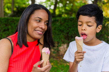 Mother and son enjoying eating ice-cream together outdoors in a park.の写真素材
