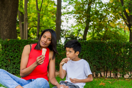 Mother and son enjoying eating ice-cream together outdoors in a park.の写真素材