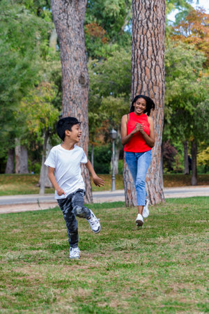Happy boy having fun running with his mother outdoors in a park.の写真素材